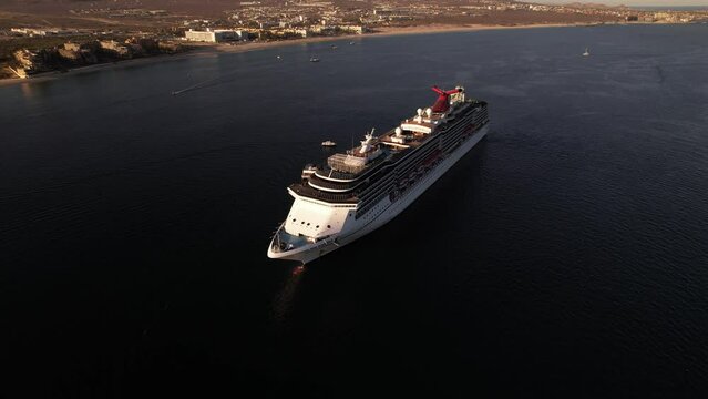 Aerial footage of a cruise ship sailing off the shore of Cabo San Lucas city on a sunny day, Mexico