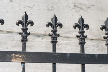 close-up of repeating decorative fence finials on a rough white background