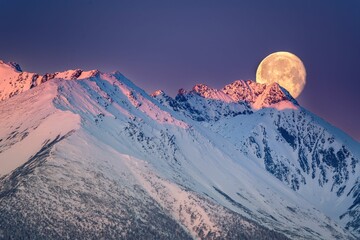 Ogromny księżyc w pełni zachodzi za Tatrami o poranku