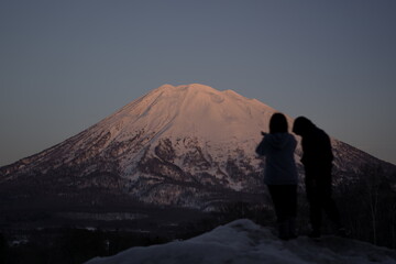 Silhouette of two individuals gazing at snowy Mount Yotei in Niseko, Japan.