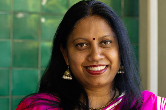 Fototapeta Indian woman wearing bright pink traditional saree, smiling at camera at home
