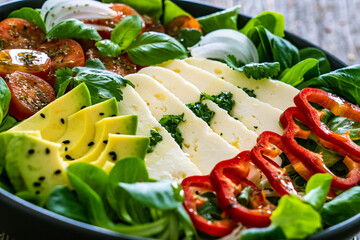 Fresh vegetable salad with robiola cheese and avocado on wooden table
