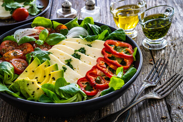 Fresh vegetable salad with robiola cheese and avocado on wooden table

