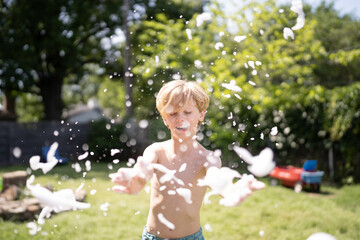 Boy playing with foam bubbles in backyard