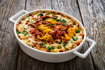 Noodle casserole with minced meat, mozzarella cheese and vegetables on wooden table
