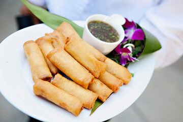Crispy spring rolls with sauce and orchid garnish.