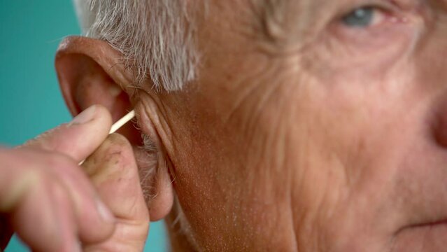 Old man is cleaning ear with a cotton swab. morning routine, personal hygiene concept