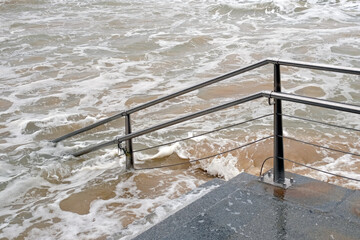 Waves flooding the stairs to the beach in San Sebastian, Spain, during high tide