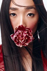 Beautiful Asian woman with long black hair holding a delicate flower in front of her face