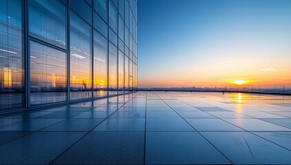 a glass building with a sunset in the background