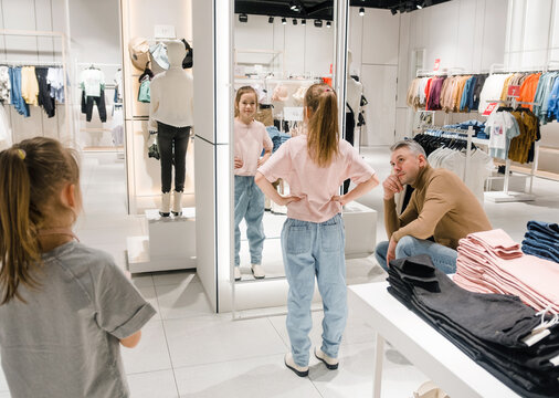 Young Girl Trying on Clothes at a Retail Store With Parent Watching