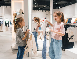 Two little girls are looking through clothes in the store, actively exploring various options