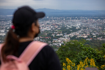 High-angle view of the city, a blurred woman standing and watching the city in the foreground. Many...