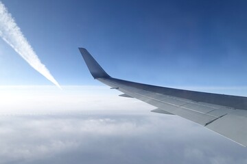 飛行機の窓から見る翼と青空と飛行機雲