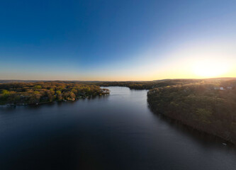 Fototapeta na wymiar Experience a tranquil escape with these serene drone views of White Meadow Lake, New Jersey. The warm hues of sunrise and sunset cast a golden glow over the placid waters, highlighting the community's