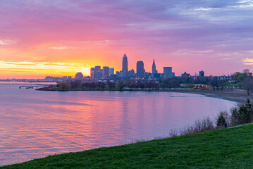 Downtown skyline silhouette behind bay with pink and yellow sunrise