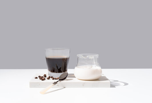 Vaso de café negro y leche sobre mármol y fondo gris