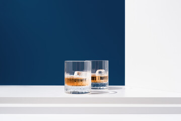 Dos vasos de whisky escocés con hielo sobre un fondo azul	