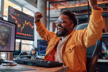 Ecstatic male stock trader in yellow jacket celebrates a successful trade in a bustling office with multiple financial charts on screens.