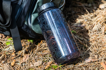 Hydration Pause: Water Bottle and Backpack Resting on Ground