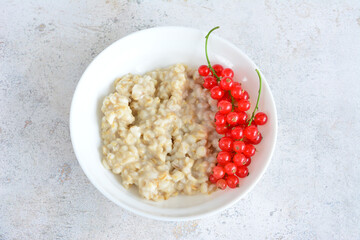 a bowl of oatmeal with clusters of red currant top view