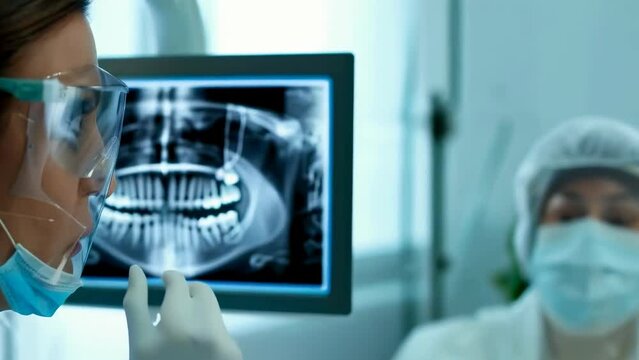 A focused dentist examining a dental X-ray, portraying the precision and expertise required in dental healthcare. Performing orthodontic surgery