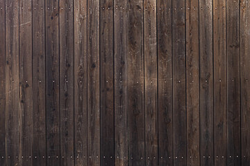 A closeup shot of a brown wooden fence with holes in the planks.