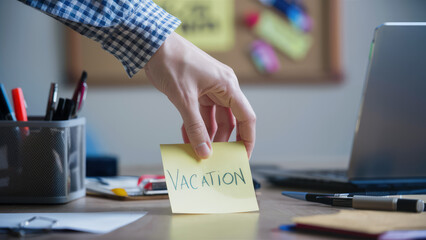 Hand Holding Vacation Sign Sticky Note at Desk
