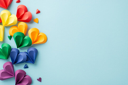 Solidarity and love: Top view of colorful hearts on pastel blue backdrop represent unity. Ideal for conveying support during Pride month. Space available for social text or promotional content