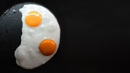 Two fried eggs in a frying pan.