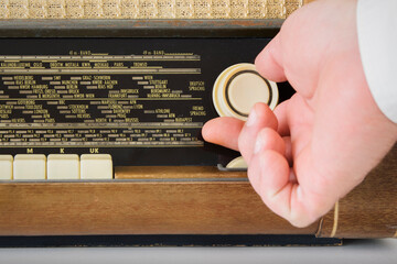 A person is adjusting the volume on a radio 50s 60s. The radio has a large number of buttons,...