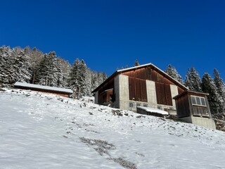 Old traditional swiss rural architecture and alpine livestock farms in the winter ambience of the tourist resorts of Valbella and Lenzerheide in the Swiss Alps - Canton of Grisons, Switzerland