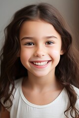 Fototapeta premium Smiling Portrait of a Young Girl with Curly Hair in a White T-Shirt Showing Her White Teeth Through Her Smile