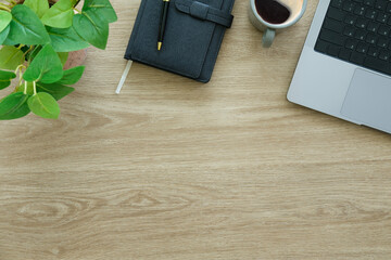 Laptop computer, coffee cup and notebook on wood background. Top view.