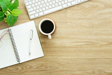 A cup of coffee, notebook, glasses and headphone on wooden table. Top view with copy space.