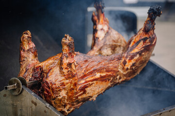 Dobele, Latvia - August 18, 2023 - A whole pig being roasted on a large barbecue grill with a...