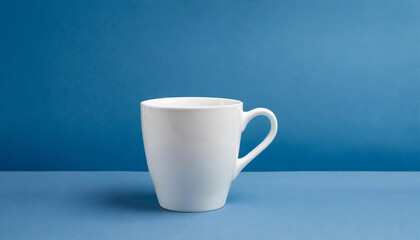 Obraz premium Close-up of ceramic white cup on isolated blue background. Tea or coffee mug. Drink ware. Mock up.