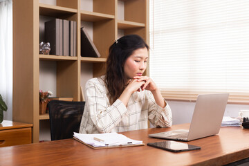 Young Asian woman in casual using a laptop working at home in living room, thoughtful freelance businesswomen sitting in office, small business architect entrepreneur concentrated planning on computer
