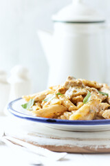 Penne Pasta baked with Meat on bright wooden Background. Close up.	