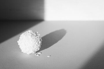 Creamy candy, monochrome. Coconut raffaello in sunlight, black and white. Simplicity concept. Sweet dessert isolated. Praline candy in sunshine with shadow.