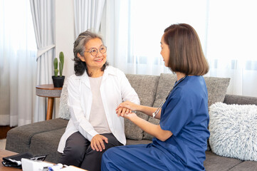 asian senior woman smiling while a young female nurse touching her hand,elderly health care at home,home visiting,home health care