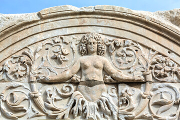 Close-up of a Medusa relief on the arch of Hadrian's Temple in Ephesus, under a bright sky. Selcuk, Izmir, Turkey (Turkiye)