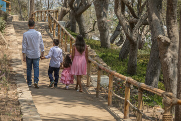 Fototapeta na wymiar Family members walking together holding hands in a sunny day in a park in Lima Peru