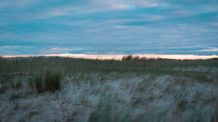 Twilight over beach dunes with tufts of grass whispering secrets to the cool breeze