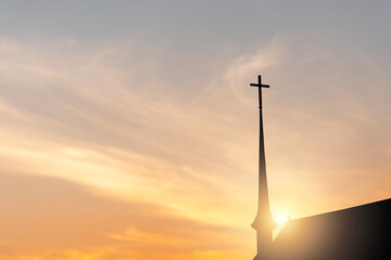 Silhouette of the cross on the church with blurred sunset background