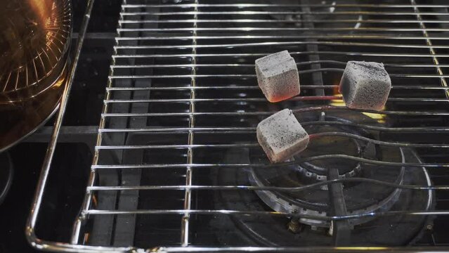 Coal for a hookah is kindled on a gas stove