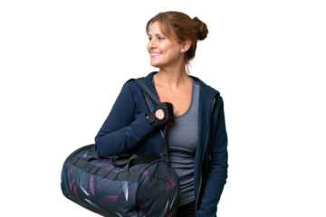 Middle-aged sport woman with sport bag over isolated background looking side