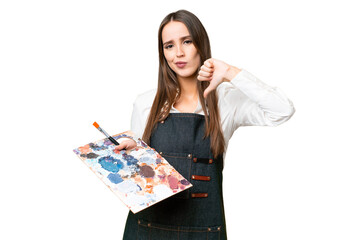 Young artist woman holding a palette over isolated chroma key background showing thumb down with negative expression