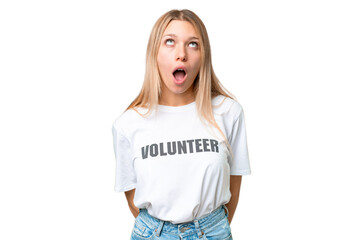 Young volunteer woman over isolated chroma key background looking up and with surprised expression