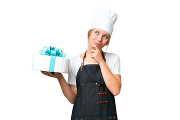 Young pastry blonde woman with a big cake over isolated chroma key background and looking up
